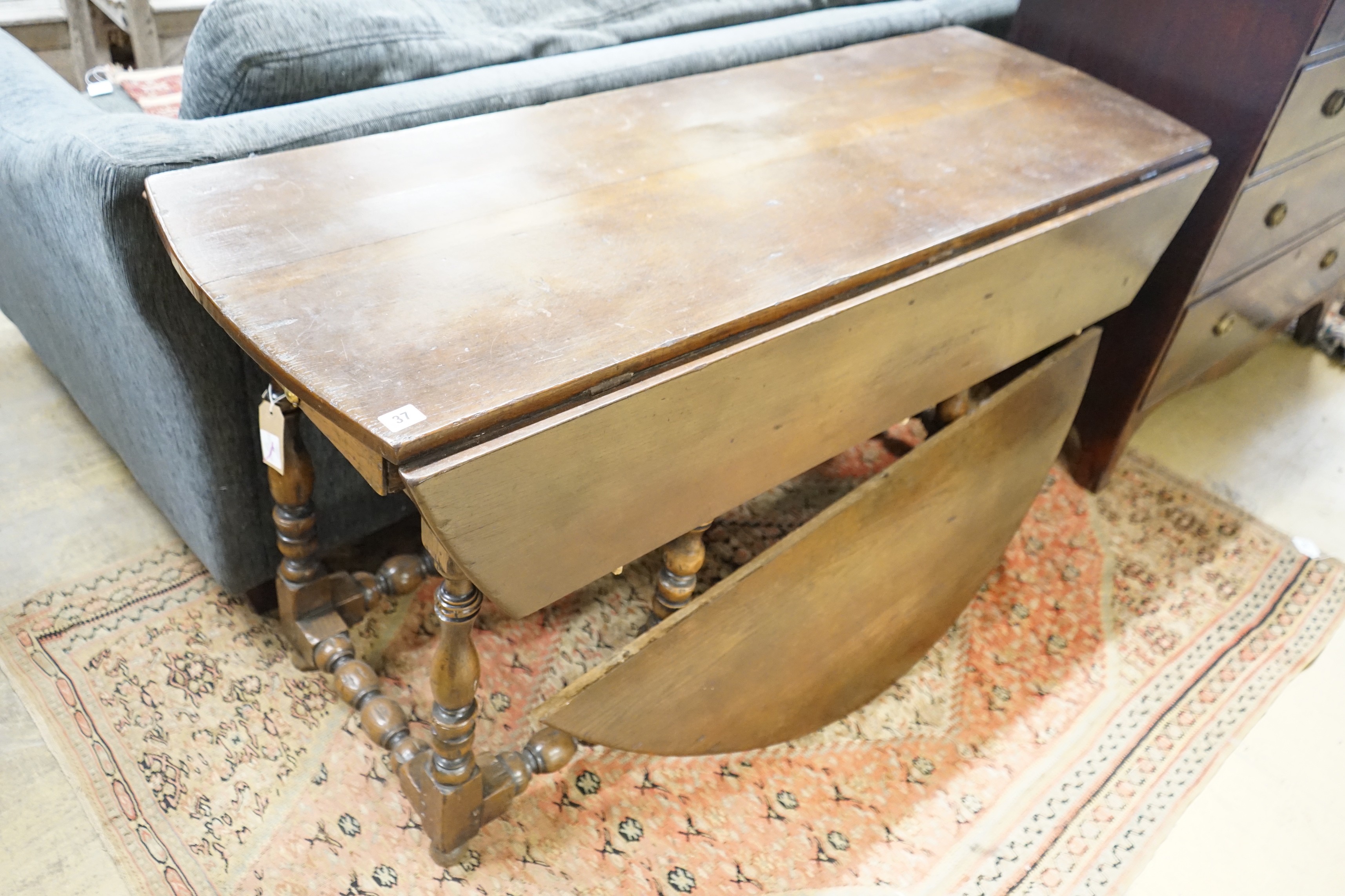 An early 18th century style oak oval topped gateleg dining table, (one leaf in need of repair), length 140cm, width 52cm, height 75cm